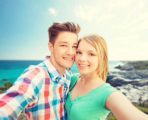 Image showing smiling couple with smartphone on summer beach