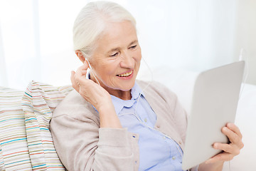 Image showing senior woman with tablet pc and earphones at home