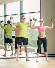 Image showing smiling man and woman with dumbbells in gym