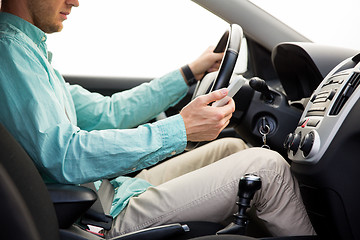 Image showing close up of man with smartphone driving car