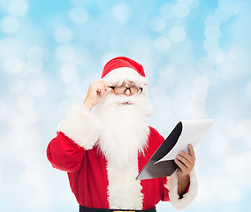 Image showing man in costume of santa claus with notepad