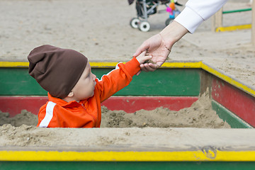 Image showing Small child in sandbox gives sand