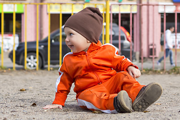 Image showing Small funny boy sits on ground