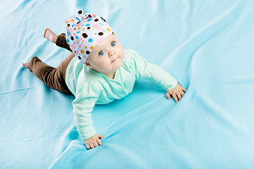 Image showing baby in hat crawling on the blue coverlet