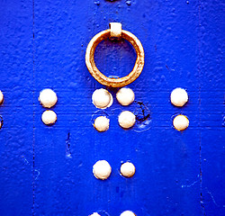 Image showing rusty metal nail dirty stripped paint in the blue wood door and 