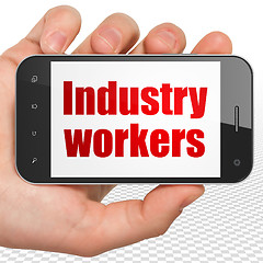 Image showing Manufacuring concept: Hand Holding Smartphone with Industry Workers on display