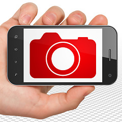 Image showing Travel concept: Hand Holding Smartphone with Photo Camera on display