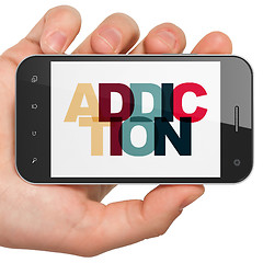 Image showing Health concept: Hand Holding Smartphone with Addiction on  display