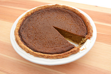 Image showing Slice cut from a pumpkin pie in a dish