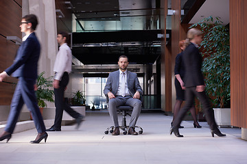 Image showing business man sitting in office chair, people group  passing by