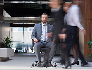 Image showing business man sitting in office chair, people group  passing by