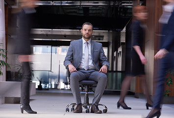 Image showing business man sitting in office chair, people group  passing by