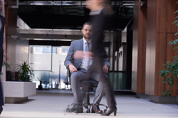 Image showing business man sitting in office chair, people group  passing by