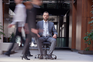 Image showing business man sitting in office chair, people group  passing by