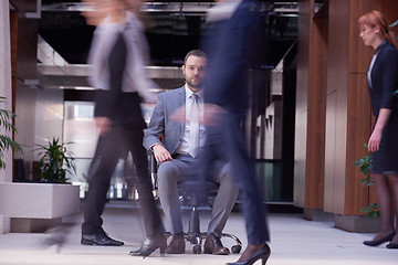 Image showing business man sitting in office chair, people group  passing by