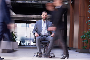 Image showing business man sitting in office chair, people group  passing by