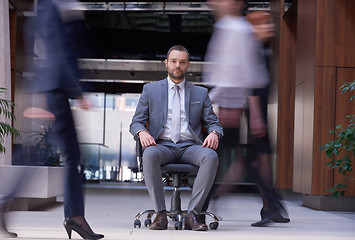 Image showing business man sitting in office chair, people group  passing by