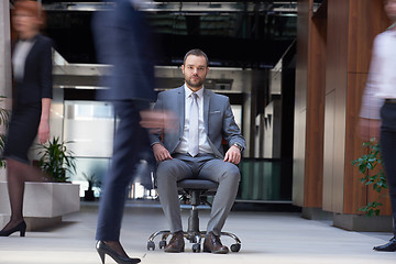 Image showing business man sitting in office chair, people group  passing by