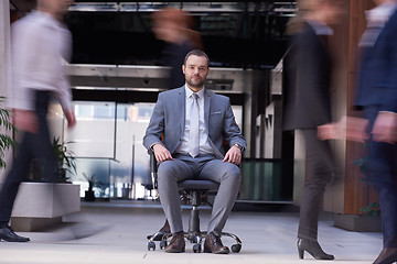 Image showing business man sitting in office chair, people group  passing by