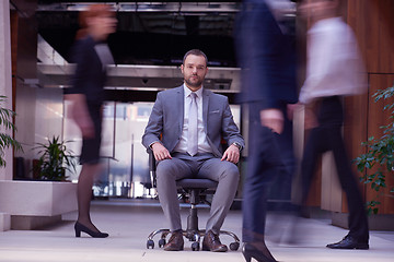 Image showing business man sitting in office chair, people group  passing by