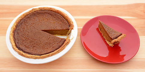 Image showing Homemade pumpkin pie with a slice served