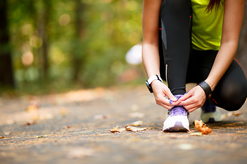 Image showing woman runner tying shoelaces