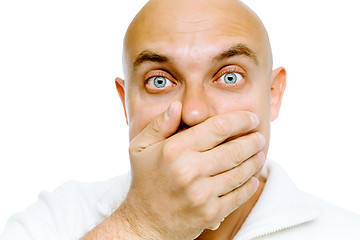 Image showing Bald frightened man in a white jacket covers her mouth with his 
