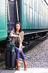 Image showing woman with a suitcase and handbag sitting on the steps of the pa