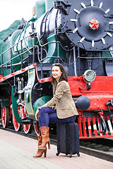 Image showing smiling beautiful middle-aged woman sitting on a suitcase