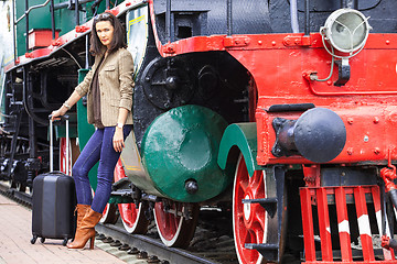 Image showing woman traveler with a suitcase near the old steam locomotive