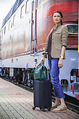 Image showing beautiful middle-aged woman with luggage near retro train