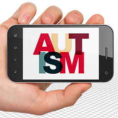 Image showing Healthcare concept: Hand Holding Smartphone with Autism on  display