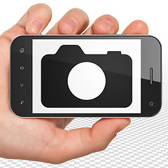 Image showing Travel concept: Hand Holding Smartphone with Photo Camera on display