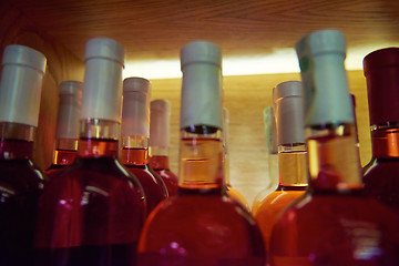 Image showing Wine bottles on a wooden shelf.