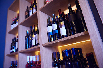 Image showing Wine bottles on a wooden shelf.