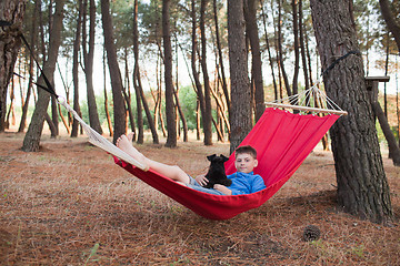 Image showing Boy and his dog relaxing in hammock