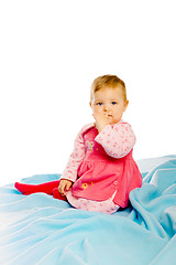 Image showing Beautiful baby sitting on a blue blanket. Studio