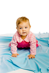 Image showing baby girl crawling on the blue coverlet. Studio