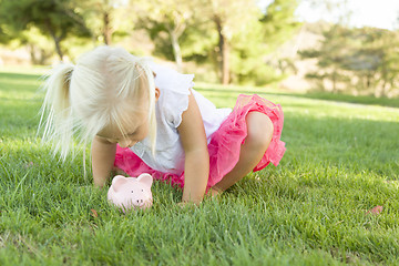 Image showing Little Girl Having Fun with Her Piggy Bank Outside