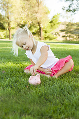 Image showing Little Girl Having Fun with Her Piggy Bank Outside
