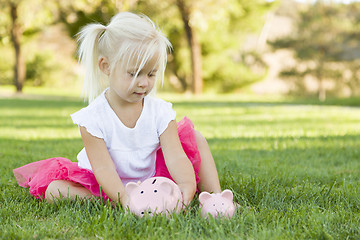 Image showing Little Girl Having Fun with Her Piggy Banks Outside