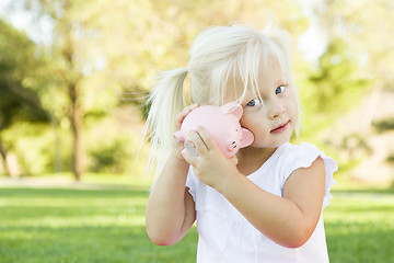 Image showing Little Girl Having Fun with Her Piggy Bank Outside