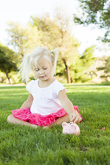 Image showing Little Girl Having Fun with Her Piggy Bank Outside