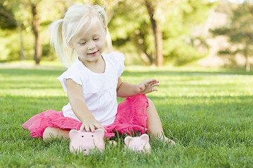 Image showing Little Girl Having Fun with Her Piggy Banks Outside