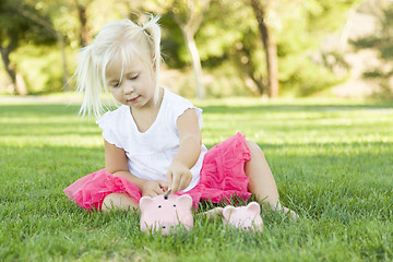 Image showing Little Girl Having Fun with Her Piggy Banks Outside