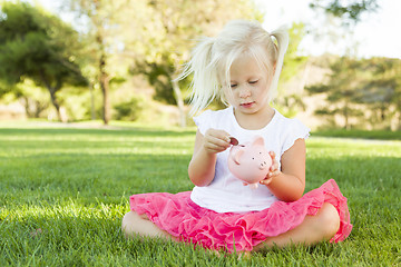 Image showing Little Girl Having Fun with Her Piggy Bank Outside