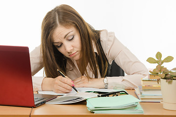 Image showing Tired teacher checks students notebooks