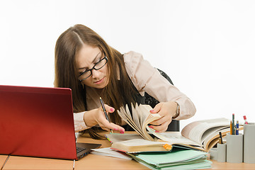 Image showing Teacher leafing through a book to find information