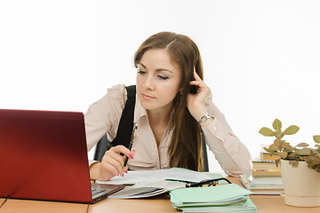 Image showing The teacher looks intently at a laptop