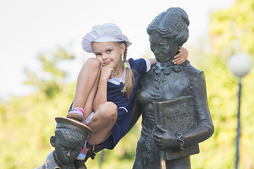 Image showing Girl thoughtfully sitting on the monument to the first teacher